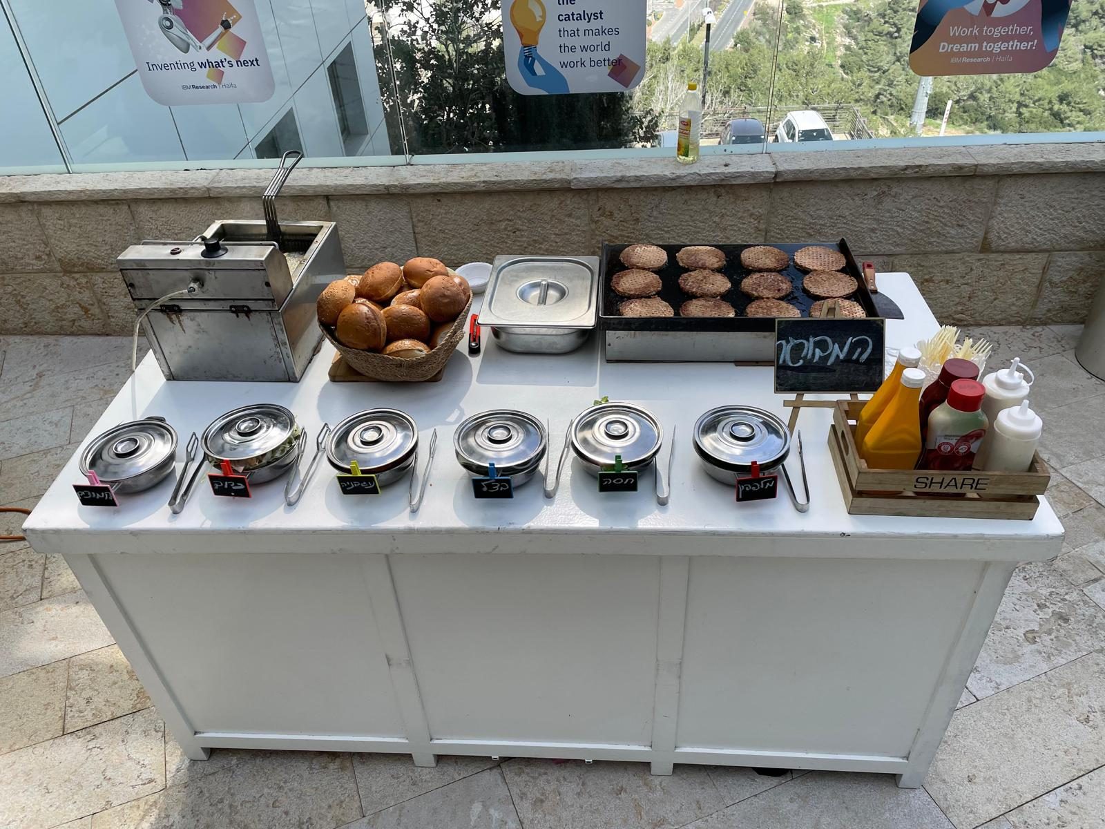 דוכן המבורגר בקר באירוע חוץ עם מגוון רטבים ותוספות